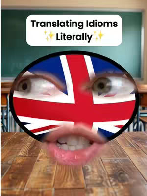 The image features a person's eyes and mouth superimposed on a stylized Union Jack flag design. Above the flag face is a white rectangular banner with the text 'Translating Idioms' and 'Literally'. The background is a blurred green chalkboard with a brown wooden desk in the foreground.