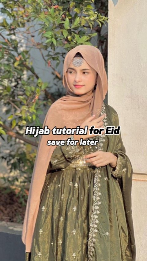 A woman with a hijab is posing outside. She wears a headscarf, a green-gold embroidered dress. The image has text overlayed.