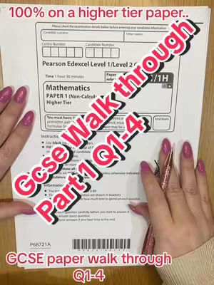 A person's hands with pink manicured nails are holding a mathematics exam paper. Text overlays indicate the video is about GCSE paper walkthrough Q1-4, and the paper is for the higher tier. The paper is white with black text, hands are placed on the paper with a pen.