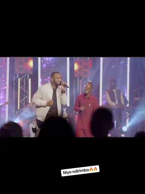 The cover image shows a live performance, with two men in the center; one is holding a microphone. Behind them are other performers and stage lighting.