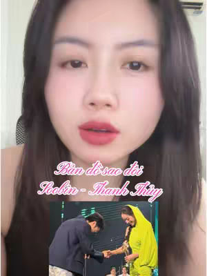 A woman with dark hair and red lipstick is in the foreground, looking directly at the camera. Beneath her, a screen displays a blurred image of a man bowing to a woman holding a microphone. Text overlays read "Bản đồ sao đời Soobin - Thanh Thủy" in a stylized pink font. The background is a light-colored wall.