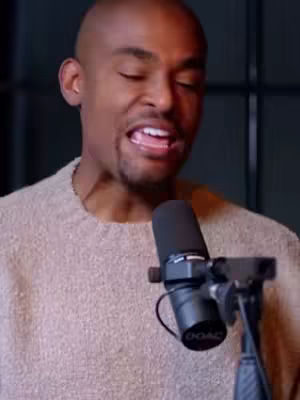 The cover image features a close-up of a man with dark skin, appearing emotional with his eyes closed and mouth open, next to a microphone. He is wearing a light-colored sweater. A microphone is positioned in front of his mouth, and the background is a dark gray. The composition emphasizes his facial expression.