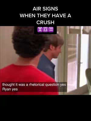 The image is a still from what appears to be a television show or movie scene. Two men are visible, one in the foreground wearing a red shirt and the back of his head is visible. The other is a man with dark hair and blue shirt in the background, slightly turned away from the camera. Overlay text at the top reads "AIR SIGNS WHEN THEY HAVE A CRUSH" with zodiac symbols below. Additional text appears at the bottom of the screen.