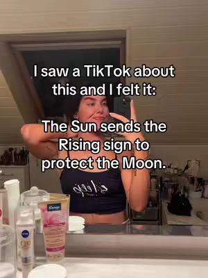 A woman takes a selfie in a bathroom, with the phone obscuring most of her face. Text overlays the image, and behind her is a mirror above a counter with cosmetics.