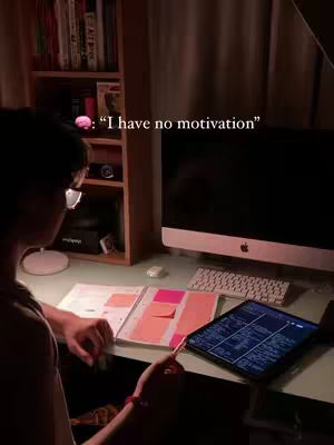 A dimly lit room with a person at a desk studying. A computer monitor, keyboard, and tablet are also visible. Text overlays are added.