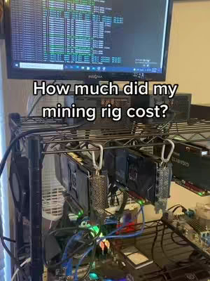 The image shows a crypto mining rig with multiple graphics cards installed on a metal rack. A computer screen is visible in the background, displaying code. The rig is lit with various cables and LED lights.