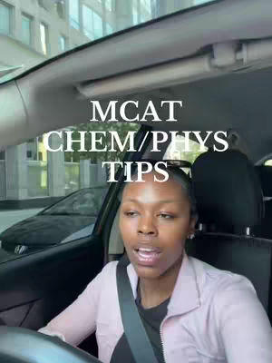 A woman is seated in a car, filming a video while driving. Text overlaid on the image reads "MCAT CHEM/PHYS TIPS". The background shows an urban street scene.