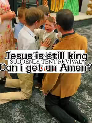 The image captures a candid moment inside what appears to be a revival setting. A young boy, visibly distressed, is being held and comforted by two adults who are kneeling. The lighting is bright, likely from overhead sources, highlighting the subjects. The overall composition creates an atmosphere of dramatic emotion and interaction within a religious context.
