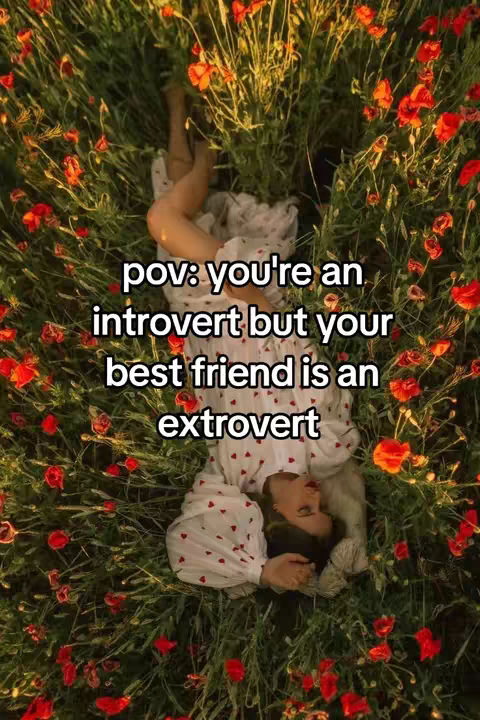 A woman lies in a bed of red flowers with her head near the bottom of the frame. Text overlays the image to emphasize the idea of introversion and extroversion.