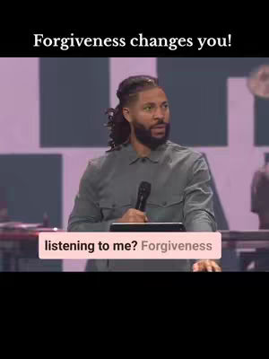 A man with a beard and short hair is speaking into a microphone on a stage. The background includes a dim, dark, and empty space. A text overlay at the bottom says 'listening to me? Forgiveness'.