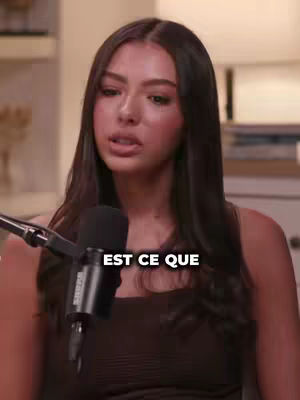 A woman with dark hair is positioned in front of a microphone, likely recording in a studio or similar professional setting. The image has a high-definition quality, with a focus on her face and upper body. At the bottom, a text overlay in white adds a question.