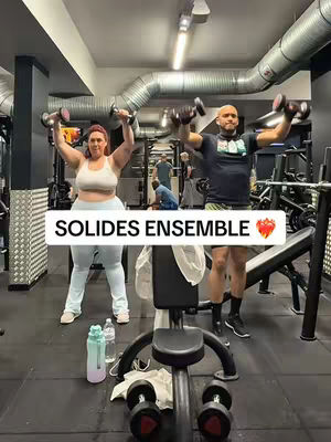 A gym scene features a man and woman lifting dumbbells. The text overlay reads 'SOLIDES ENSEMBLE' and has a heart emoji. They are in a gym.