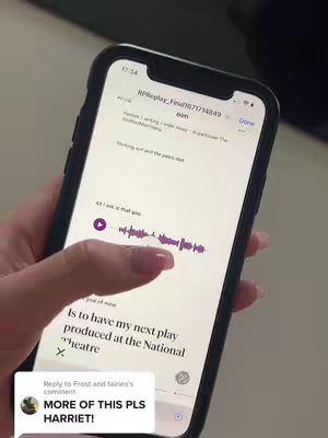 A hand holding a smartphone displaying a document. The phone is angled towards the viewer, revealing a text document with some text, a play button, and a waveform. The person's fingers are visible, lightly touching the screen, while there's a comment section with an profile image and comment on the screen