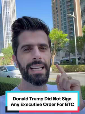 A man with dark hair and a beard stands outside, pointing to the side. He wears a white shirt and has an earpiece in his left ear. The background includes buildings and a glimpse of a road. Text overlayed on a blue rectangle says: Donald Trump Did Not Sign Any Executive Order For BTC