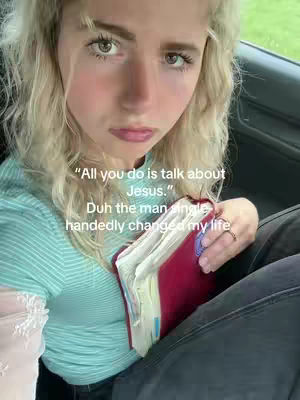 A woman with blonde hair and a light blue striped shirt holds a red book, possibly a Bible, in her lap. Text overlays the image.