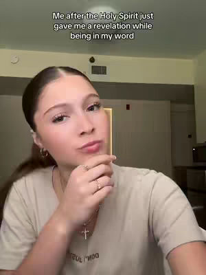 A woman with dark hair, wearing a light-colored shirt, is looking at the camera with a hand near her chin. Text overlayed at the top says, “Me after the Holy Spirit just gave me a revelation while being in my word.” The background is blurred, showing an interior setting lit with a warm color temperature.