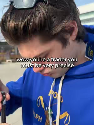 A young man with short brown hair is seen from the chest up, angled slightly downwards. He's wearing a blue hoodie with the Polo Ralph Lauren logo prominently displayed. Text overlayed on the image reads, WOW you're a trader you must be very precise. Goggles are perched on top of the man's head. The background is blurred and the lighting seems natural.