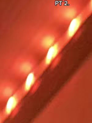 An abstract image with a warm color palette. The majority of the image is filled with a gradient of orange and red hues. Diagonal across the image is a strip of lights, with each light having a yellow center and a surrounding of white light.