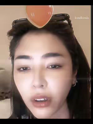 The cover image is a selfie of a woman in close-up. She has dark hair with sunglasses on top of her head, a heart graphic above her forehead, and is looking at the camera with her mouth slightly open. The background is blurred with warm tones.