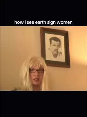 The cover image shows a person with blonde hair and glasses looking at the camera. Above them, on the beige wall, is a framed picture of a man. The text overlay says: "how I see earth sign women".
