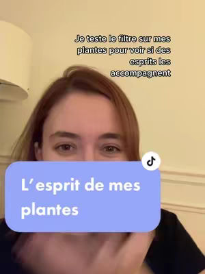 A woman with light brown hair is centered in the frame, looking towards the viewer. Overlayed on the image is a light blue rectangular text box with rounded corners. Inside the box, the text reads "L'esprit de mes plantes" in white font. Above the woman's head, there's another text overlay in black, which reads "Je teste le filtre sur mes plantes pour voir si des esprits les accompagnent", and a small TikTok icon at the right.