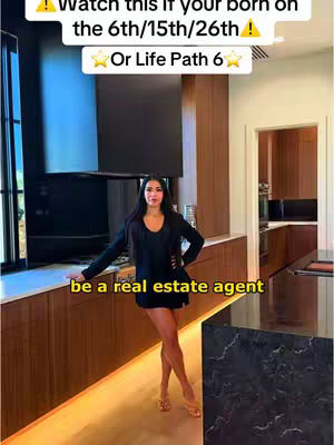 A woman stands in a modern kitchen with dark cabinetry and a black countertop. The image is brightly lit, and text overlayed, suggesting real estate.