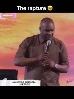 A middle-aged Black man wearing a brown short-sleeved button-down shirt gives a speech into a microphone. He stands on a stage in front of a blurry background of yellow and pink hues. Text on the image includes 'The rapture' at the top and a logo reading 'MIRACLE TV'. The bottom of the screen has a banner that reads 'APOSTLE JOSHUA SELMAN'.