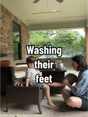A person washes a child's feet on a patio; text overlay: 'Washing their feet'.
