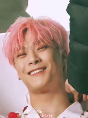 The cover image features a smiling young man with dyed pink hair. He has his eyes closed and is showing off his smile. The background is blurred light. The person is wearing a white shirt and what appears to be a red object around the neck.