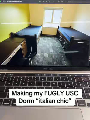 The cover image shows a laptop displaying a dorm room interior. The shot is taken from a slightly elevated angle, facing the room, viewed behind the laptop. The room is brightly lit with natural light entering through a window. The walls in the background are shades of olive green, with the rooms containing two black bed frames, dark wooden drawers and desks, and a dark grey carpet The image is framed by the edges of the laptop.