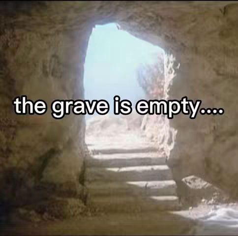 A cavern interior forms the backdrop. The entrance is framed by rough stone, which leads to a bright blue sky. A set of steps is visible leading into the cave. The words 'the grave is empty…' are in white text overlayed in a curved text over the image.