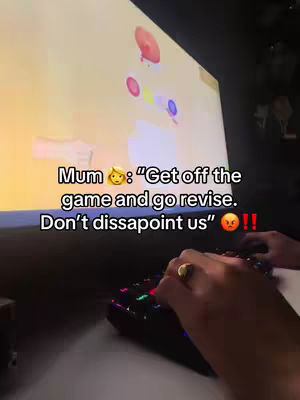 A person's hands are shown on a gaming keyboard, with a computer screen in the background. The on-screen graphics suggest a game with colorful, circular elements. The upper portion of the image features overlaid text against a background that appears to be a wall.