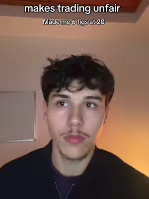 A young man with short dark hair and a mustache is centered in the frame, looking slightly to the side. The background is a warm beige and a white board is visible on the left.