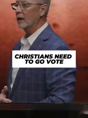 A man wearing glasses and a blazer is speaking into a microphone on a podium, with a white rectangular overlay that says 'CHRISTIANS NEED TO GO VOTE'. The background is a gradient of orange and red.